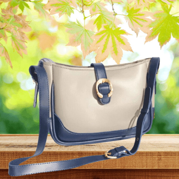 Elegant beige and navy moon-shaped handbag with gold buckle and shoulder strap
